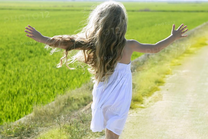 Rear view running open arms little happy girl green meadow field track
