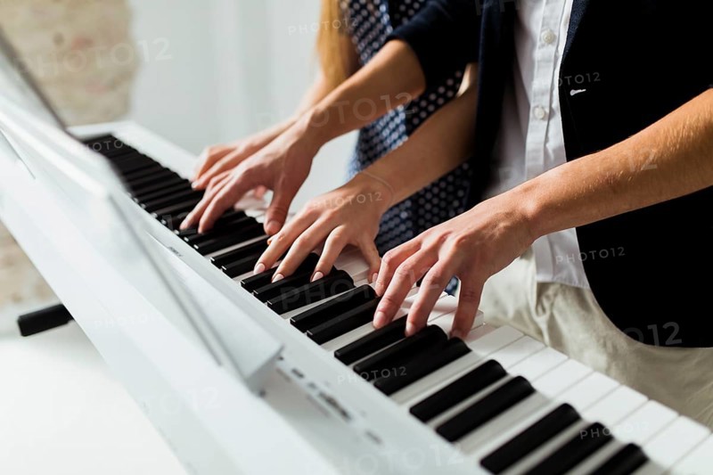 Close up couple s hand playing piano keyboard