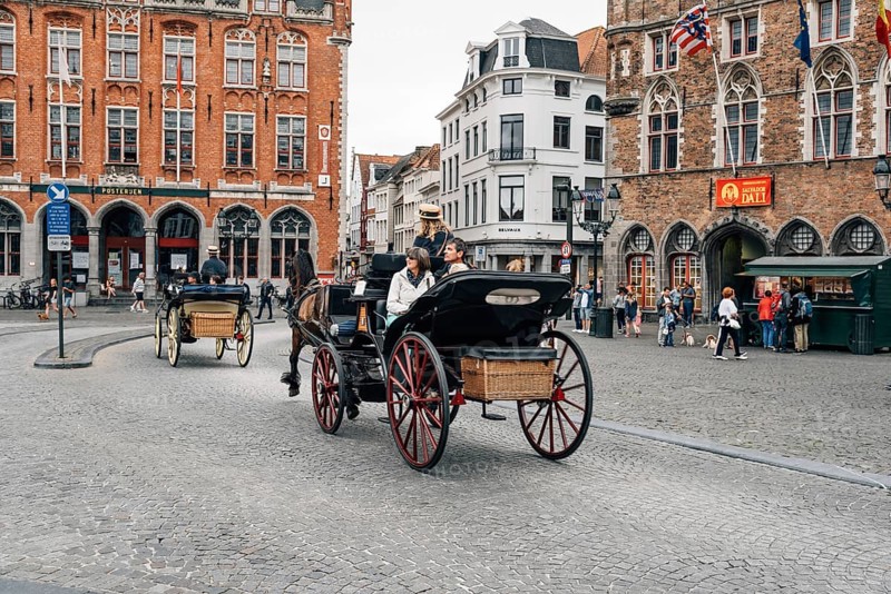 Bruges, Belgium, July 29, 2016: Horse carriage for tourists in Markt Square in the city of Bruges. The historic city centre is a World Heritage Site of UNESCO. It is known for his picturesque cobbled lanes and dreamy canals, Europe