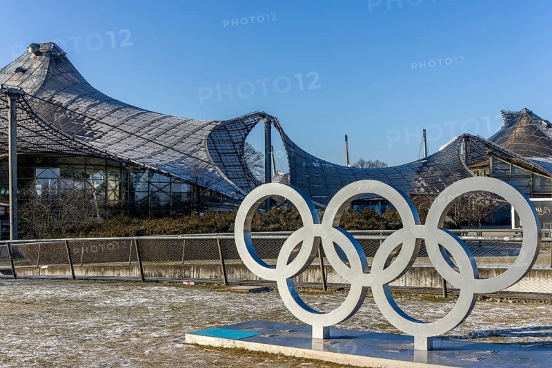 Sculptures of the Olympic rings and in the background the Olympic site with the Olympic buildings with blue sky in the background, Munich, Upper Bavaria, Bavaria, Germany, Europe
