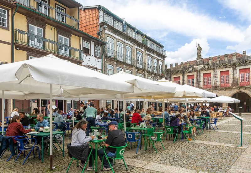 Tables and chairs, historic buildings in Largo da Oliveira square, city of Guimaraes, northern Portugal