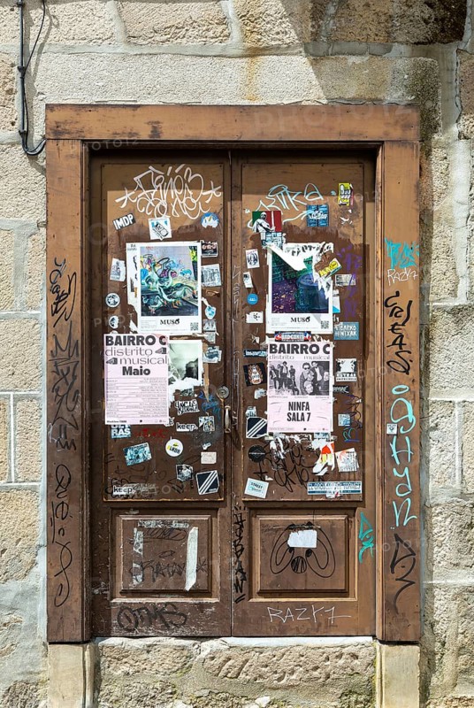 Stickers posters and graffiti tags on old wooden door, Guimaraes, Portugal, Europe