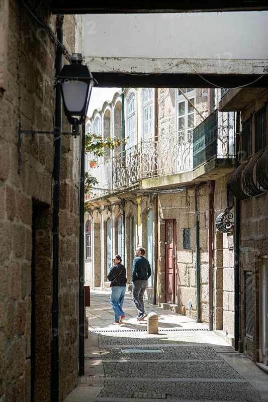Coupe walking exploring alleyways in historic centre of ity of Guimaraes, northern Portugal