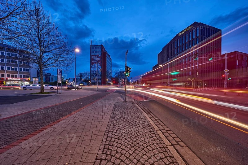 General architecture, modern building, bare wintry trees, traffic lights, pavement made of paving slabs, asphalt, car headlights, light traces, blue hour in the evening, blue evening sky, cumulus clouds, intersection between Celler Straße, Goseriede and Otto-Brenner-Straße, Hanover, state capital, Hanover region, Lower Saxony, Germany, Europe