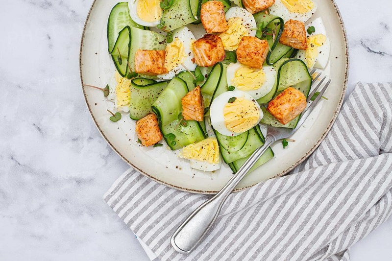Delicious salmon and egg salad served on a plate with fresh cucumber and herbs for a healthy meal at lunchtime
