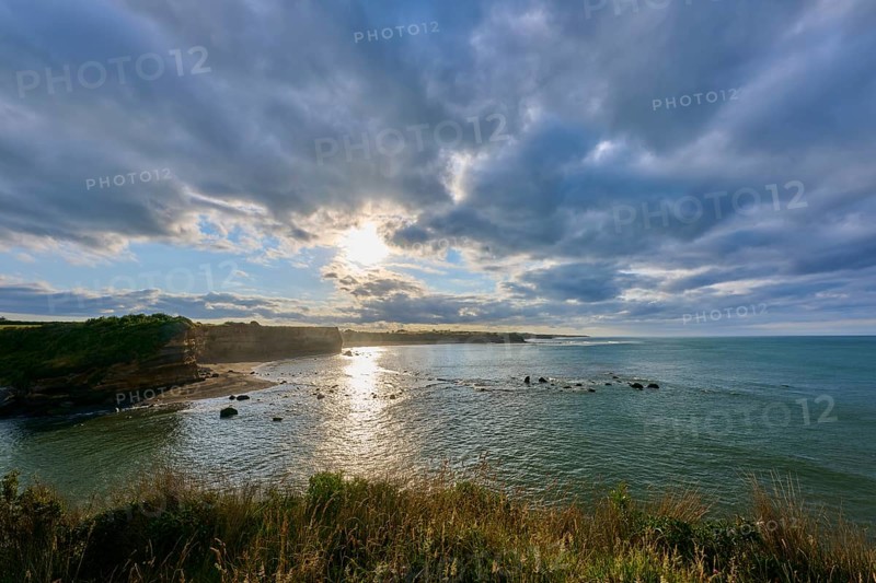 Sunrise over calm sea, dramatic clouds and light reflections, Opunake, Taranaki, North Island, New Zealand, Oceania