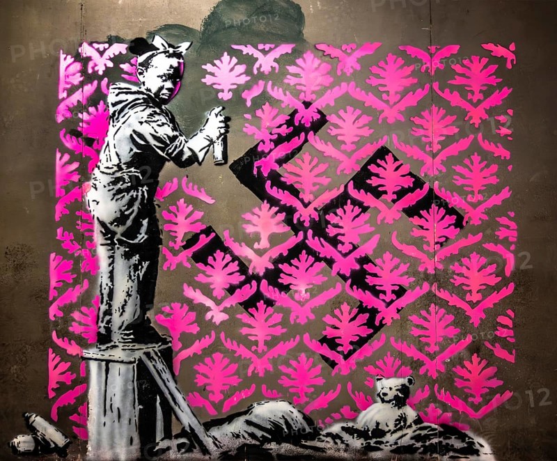 Banksy - Migrant Soup Citchen, Girl trying to remove a swastika, protest against injustice towards refugees, 2018, Porte de la Chapelle, Paris, France, exhibition The World of Banksy, Europe