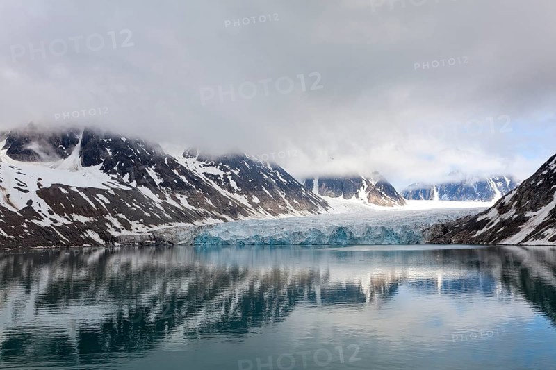 An impressive lake reflects the surrounding glaciers and mountains, surrounded by clouds and a calm atmosphere, Magdalenenfjord with Waggonway Glacier, Svalbard, Norway, Europe