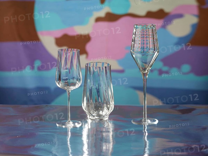 Various glasses on silver foil, behind them various colour elements, studio shot