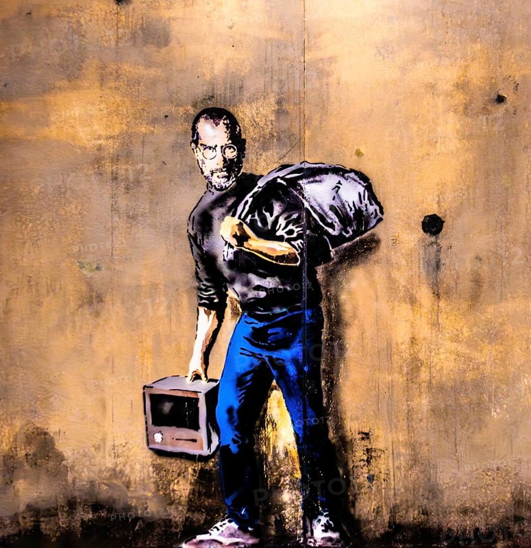 Banksy - Steve Jobs as a Syrian refugee in a refugee camp, 2015, The Jungle Refugee Camp, Calais, France Exhibition The World of Banksy