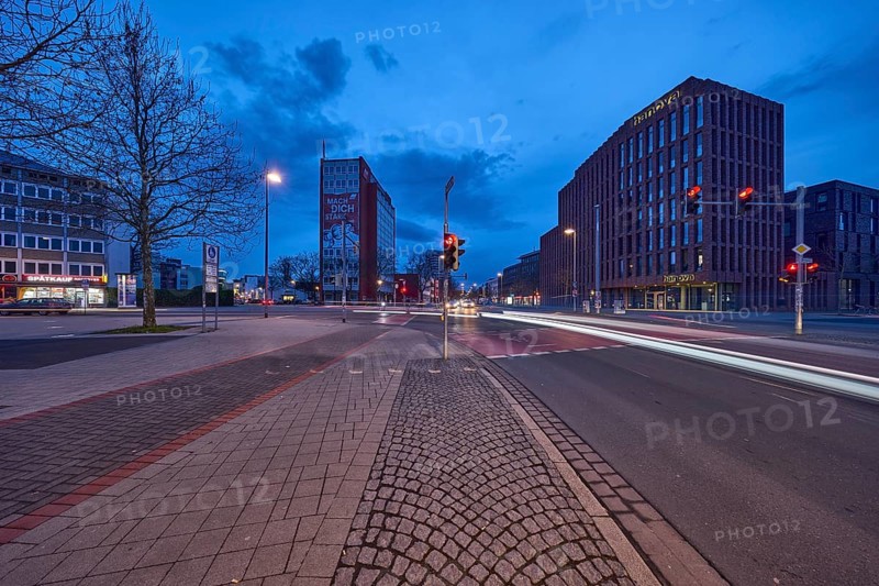 General architecture, modern building, bare wintry trees, traffic lights, pavement made of paving slabs, asphalt, car headlights, light traces, blue hour in the evening, blue evening sky, cumulus clouds, intersection between Celler Straße, Goseriede and Otto-Brenner-Straße, Hanover, state capital, Hanover region, Lower Saxony, Germany, Europe