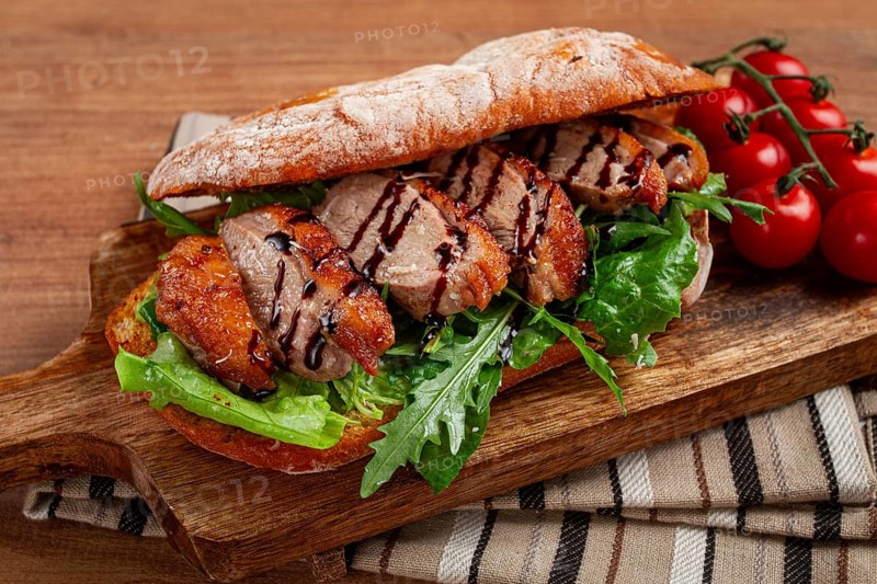 Sandwich with duck breast and arugula, balsamic sauce, on a wooden chopping board, breakfast, homemade, without people
