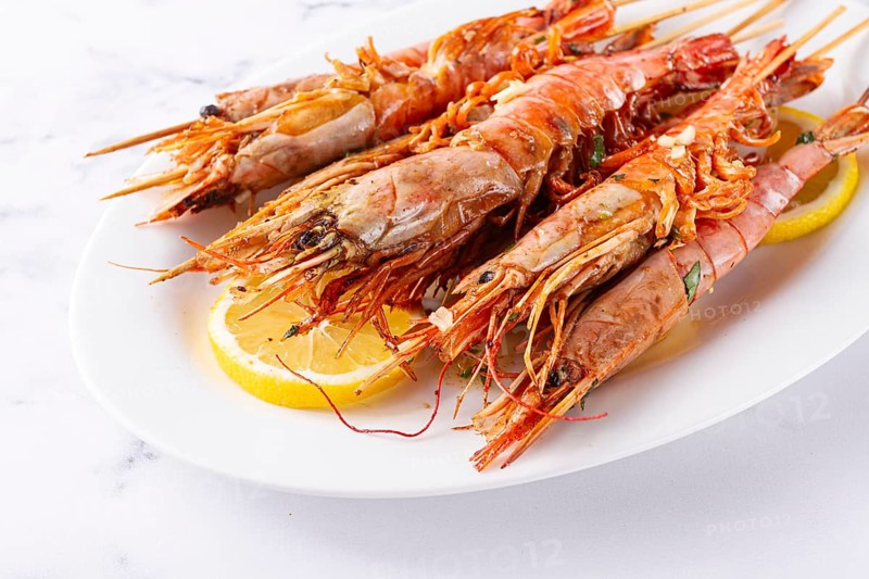 Freshly grilled prawns served, on a white platter, with lemon slices, for a delicious seafood experience