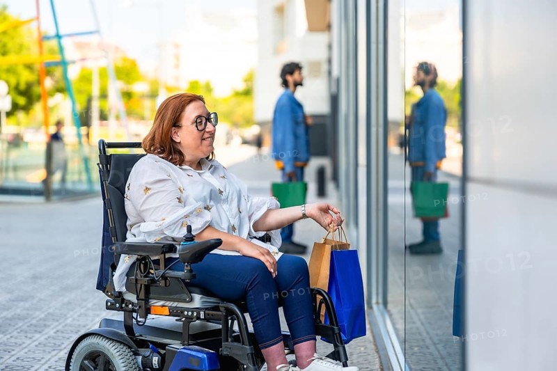Smiling woman in a wheelchair holding shopping bags enjoying a day of shopping in a modern city