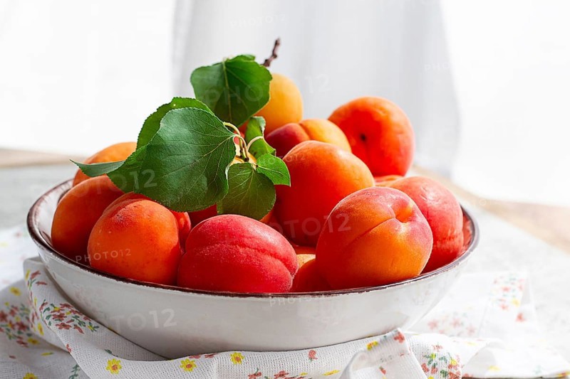 Fresh apricots in a bowl, on a bright table, natural light, top view, no people