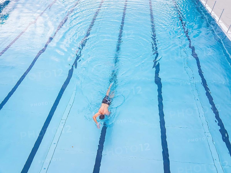 A person swims along the lanes in a large, blue swimming pool, outdoor pool Calw, Black Forest, Germany, Europe