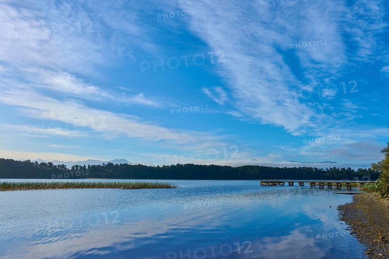 A long jetty on the shore of a calm lake under an overcast sky, Lake Mahinapua, Ruatapu, South Island, New Zealand, Oceania