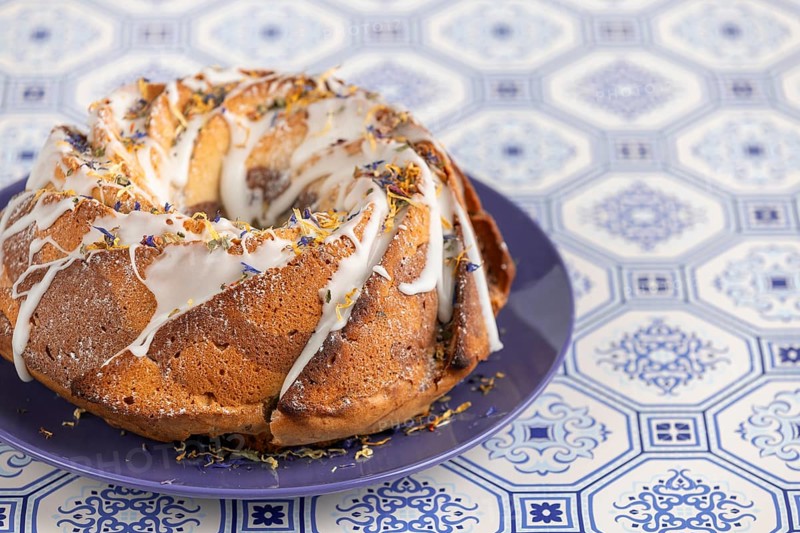 Marble bundt cake, cake with icing and edible flowers on a blue plate