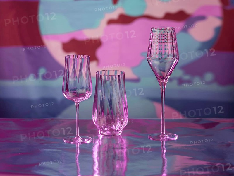 Various glasses on silver foil, behind them various colour elements, studio shot
