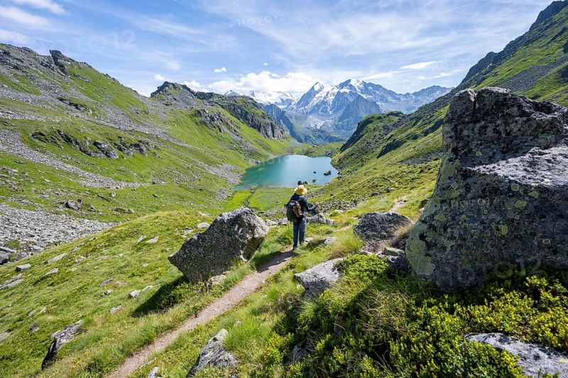 Mountaineer on hiking trail in picturesque mountain landscape, view of mountain lake Lac du Louvie and glaciated mountain peaks of the Grand Combine, Valais Alps, Val de Bagnes, Valais, Switzerland, Europe