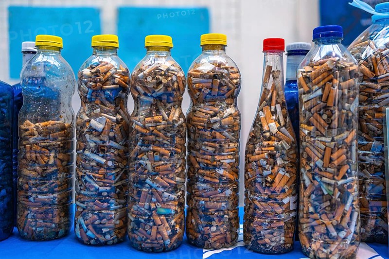 Plastic bottles filled with cigarette butts collected during a beach cleanup highlight environmental pollution and human impact