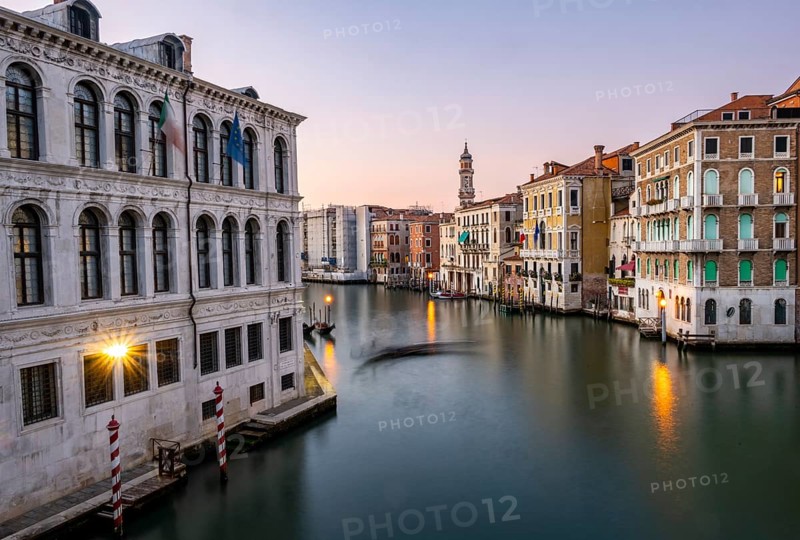View of the Grand Canal with gondoliers at sunset, picturesque evening mood with illuminated palazzos on the canal and church tower of the Chiesa Parrocchiale dei Santi Apostoli, long exposure, view from the Rialto Bridge, Venice, Veneto, Italy, Europe