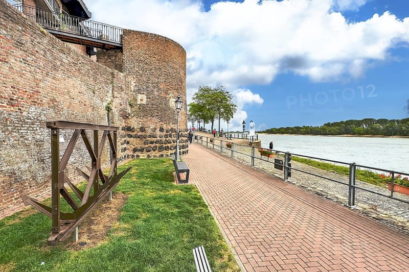 View of historic town wall and former customs tower for customs duties on the Rhine promenade of Rees on the Lower Rhine, old anchors on the left in the foreground, Rhine river on the right, Rees, North Rhine-Westphalia, Germany, Europe