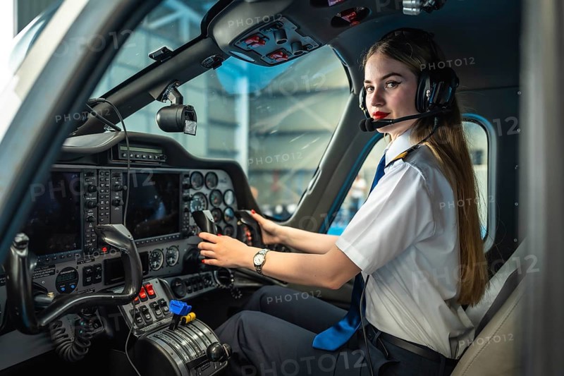 Young woman pilot sitting in the cockpit of a modern aircraft, adjusting controls and preparing for flight takeoff