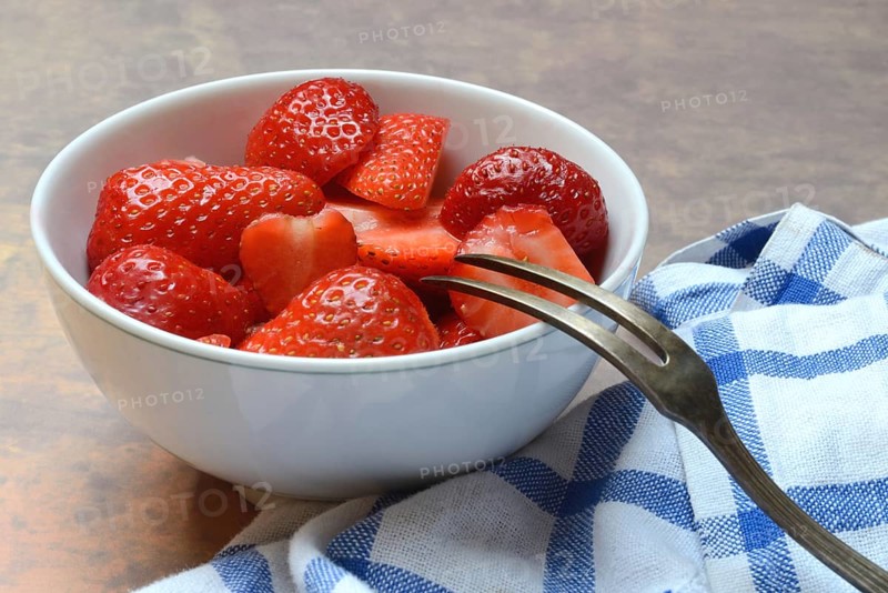 Sliced strawberries in hull with fork, Fragaria