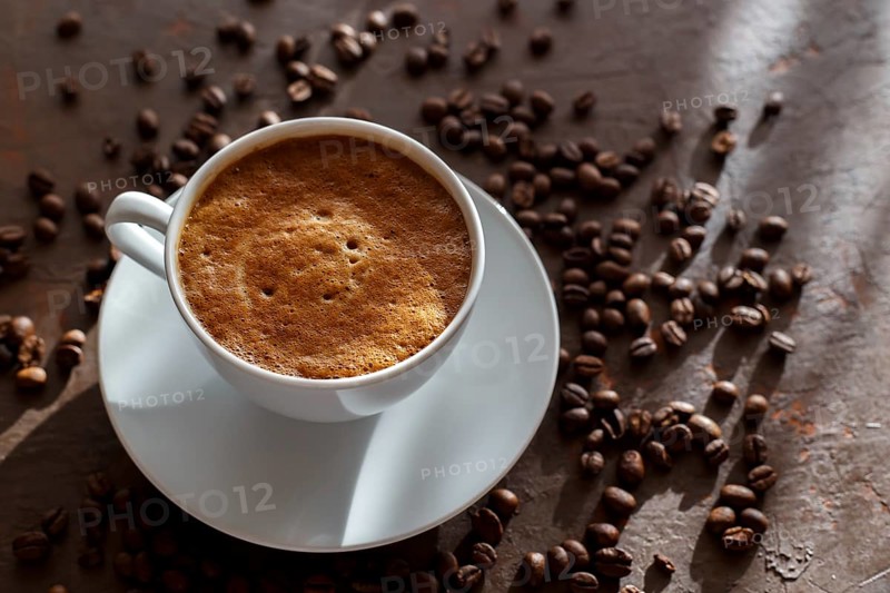 Cup of coffee cappuccino and coffee beans on the brown stone background