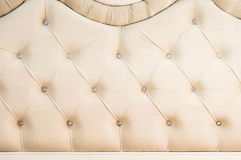 Beige soft textile background with symmetrical buttons on the corners of diamonds. Soft and expensive furniture elements. Luxury background