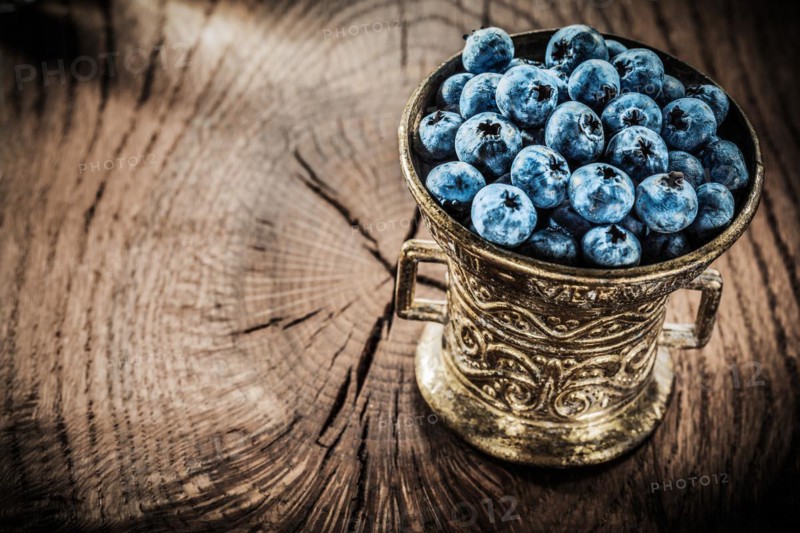 Blueberries in vintage metal bowl on grunge board