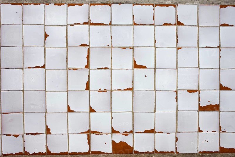 An old white obsolete and damaged tiled wall, good as a texture or background design element