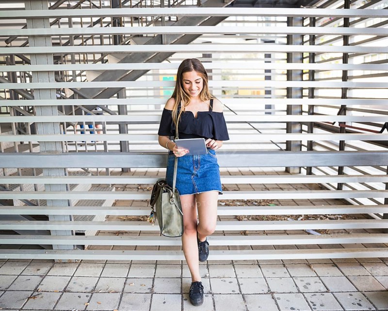 Young woman with bag using tablet university