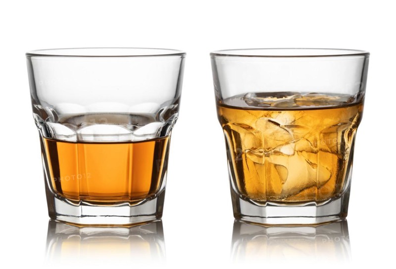Glass of whisky and ice isolated white background