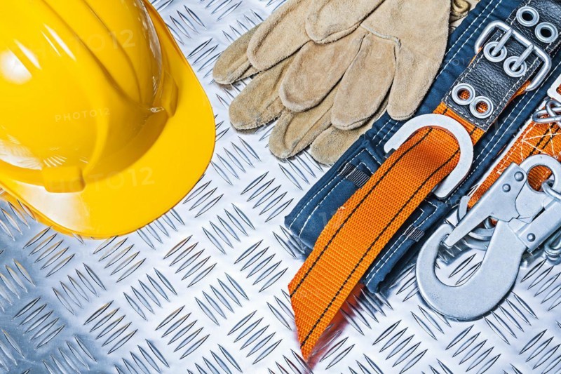 Yellow helmet, safety harness and gloves on corrugated metal plate