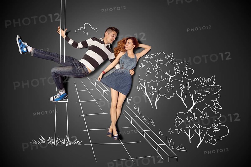 Happy Valentine's Day love story concept of a romantic couple against chalk drawings background. Male pole dancing on a lamppost while walking with girlfriend
