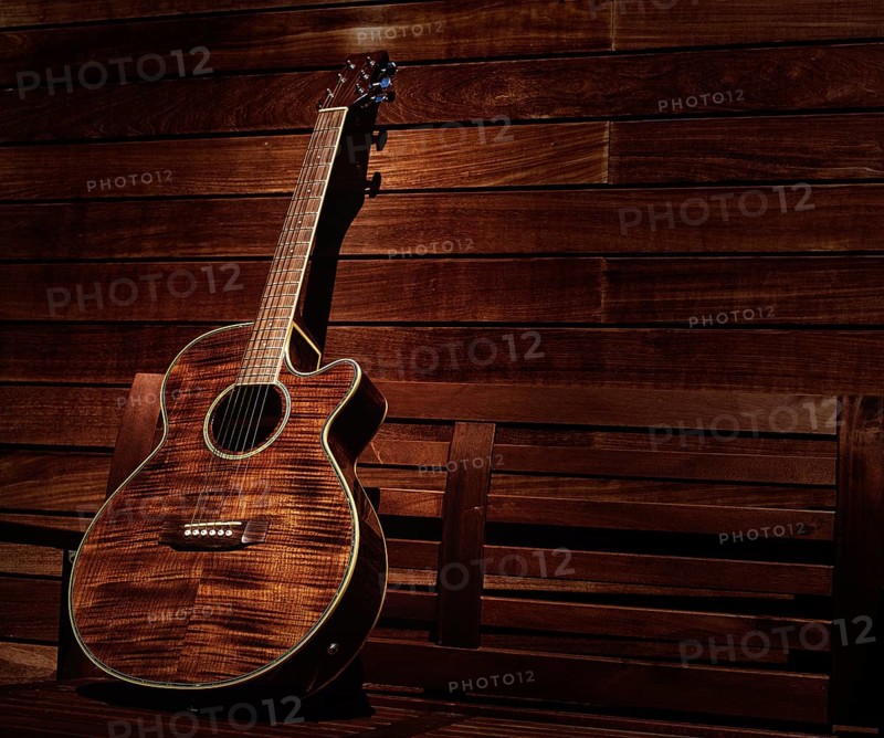 Acoustic brown guitar in a wooden stripes wooden wall monochromatic