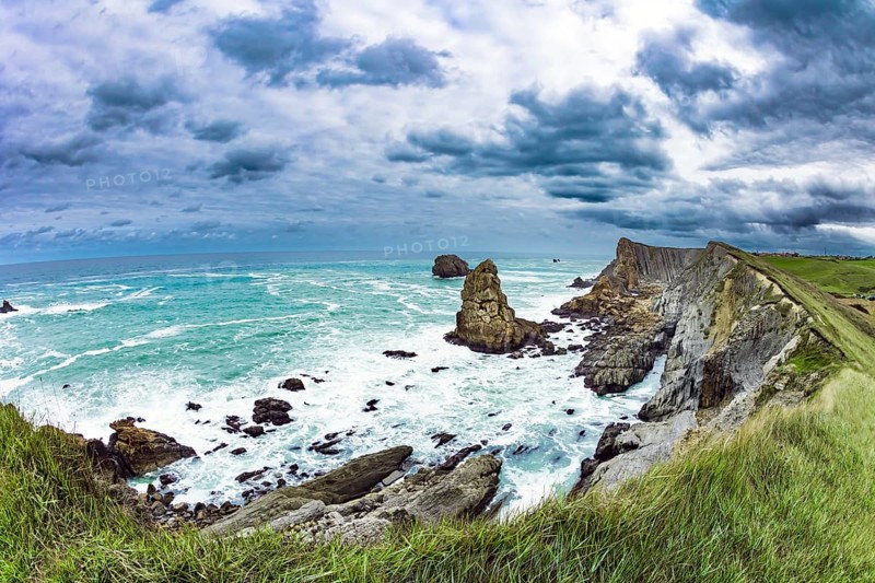 Powerful surf waves with a foam crest. Dramatic stormy sky. Cantabria Beaches, Portio Beach. Windy stormy day on the Atlantic coast. Noon on the beach of Playa di Arnia, Spain, Europe