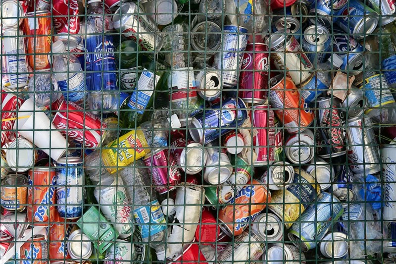 Assorted beverages cans on the trash, colored texture