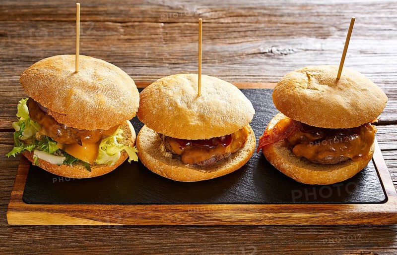 Burger in a row on a slate board and wood table