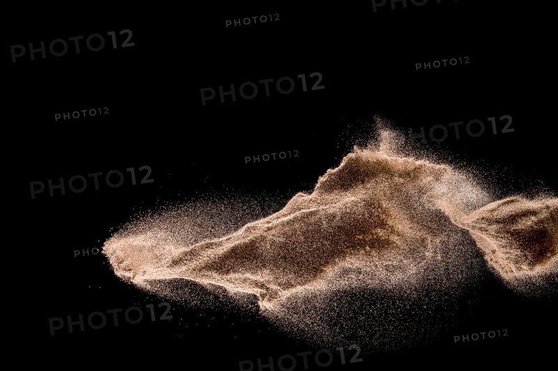 Dry river sand explosion. Golden colored sand splash against dark background