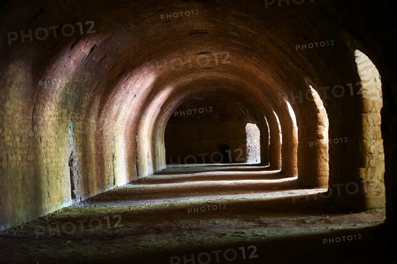 Light falls through arched niches into a tunnel-like cellar wall
