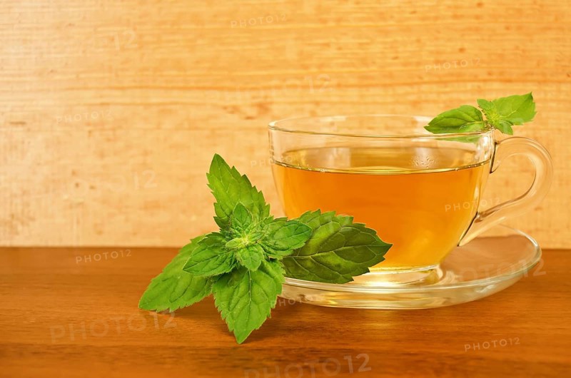 Herbal tea in a glass cup with mint on a table on a background of wooden boards