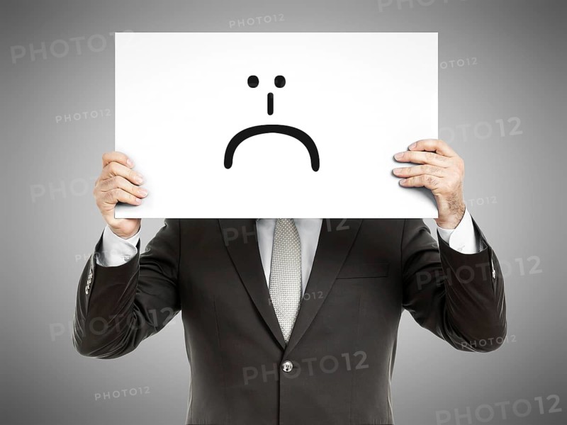 A business man holding a paper in front of his face with a smiley sign on it