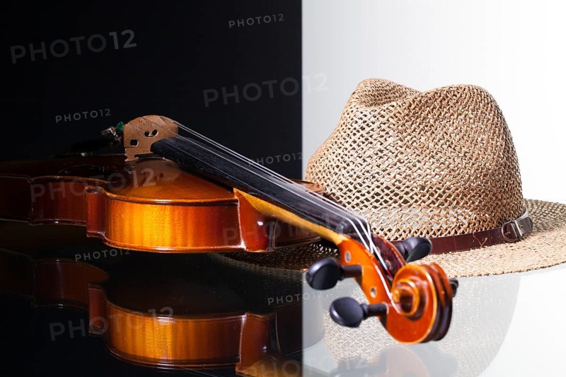 Old violin and straw hat isolated on black and white background and glass desk