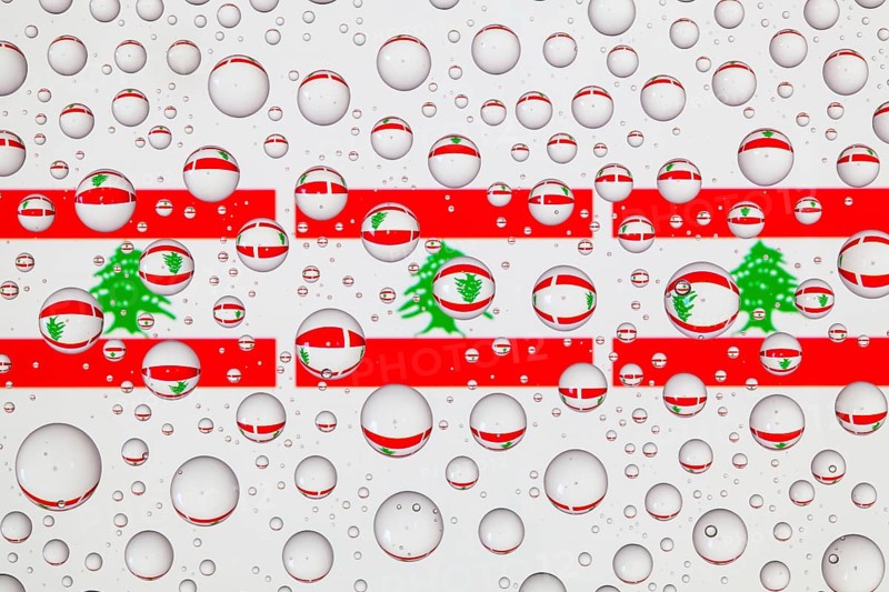 Flags of Lebanon behind a glass covered with raindrops. 3D illustration