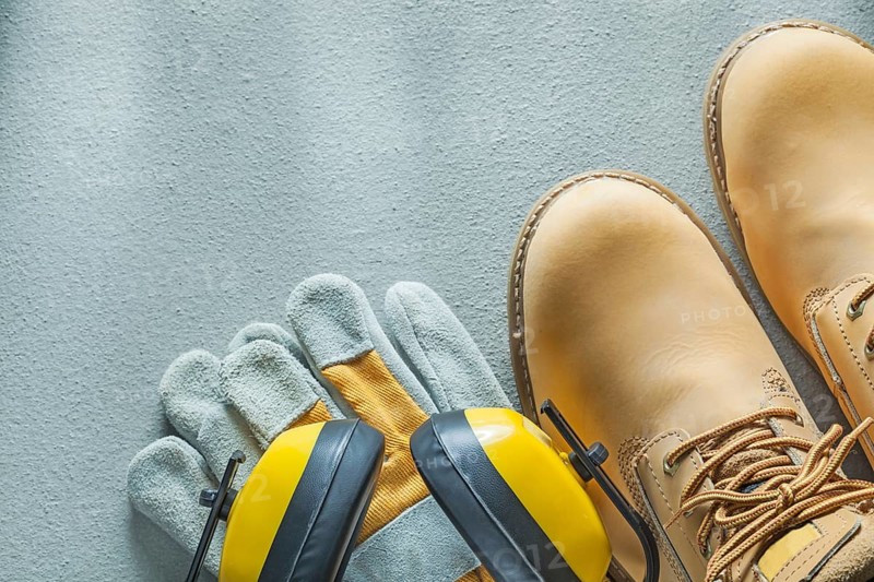 Safety lace boots protective gloves earmuffs on concrete background