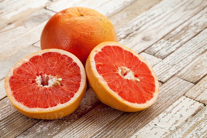 Red cut grapefruit on white grunge wood table with paint peeling off