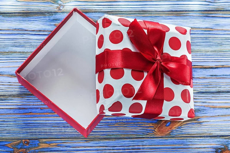 Opened gift box with bow on vintage wooden board